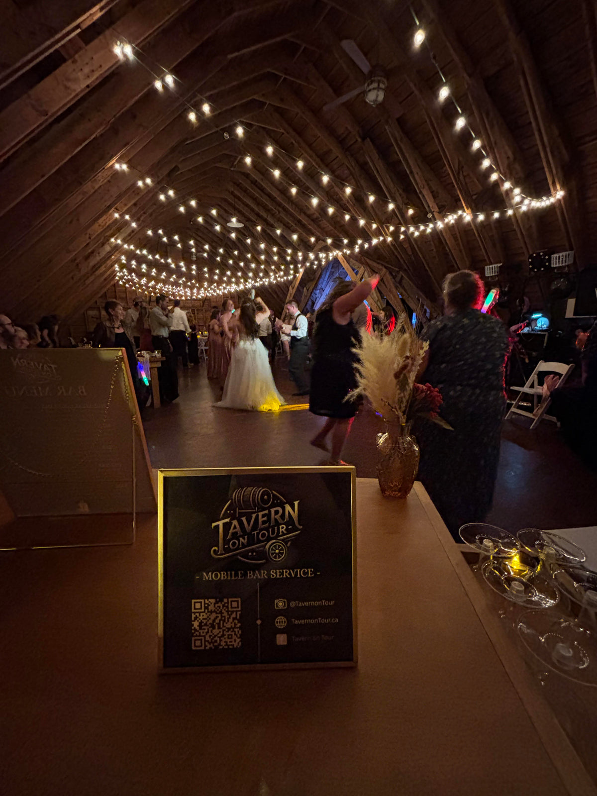 Dance floor with string lights and people at a wedding reception, featuring a 'Tavern on Tour' sign in the valley, nova scotia